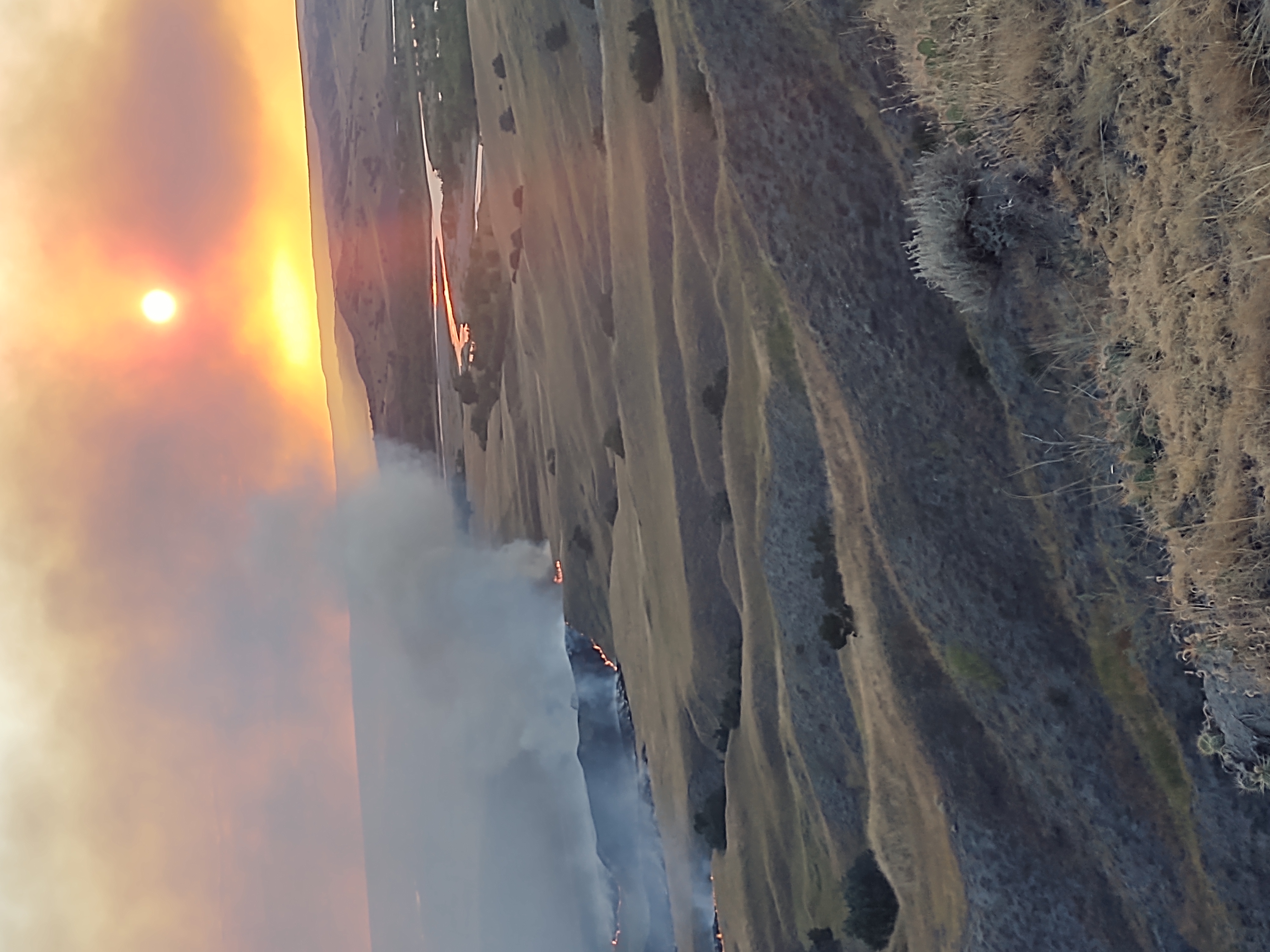 Aerial image of grassland fire burning with clouds of smoke obscuring the sun