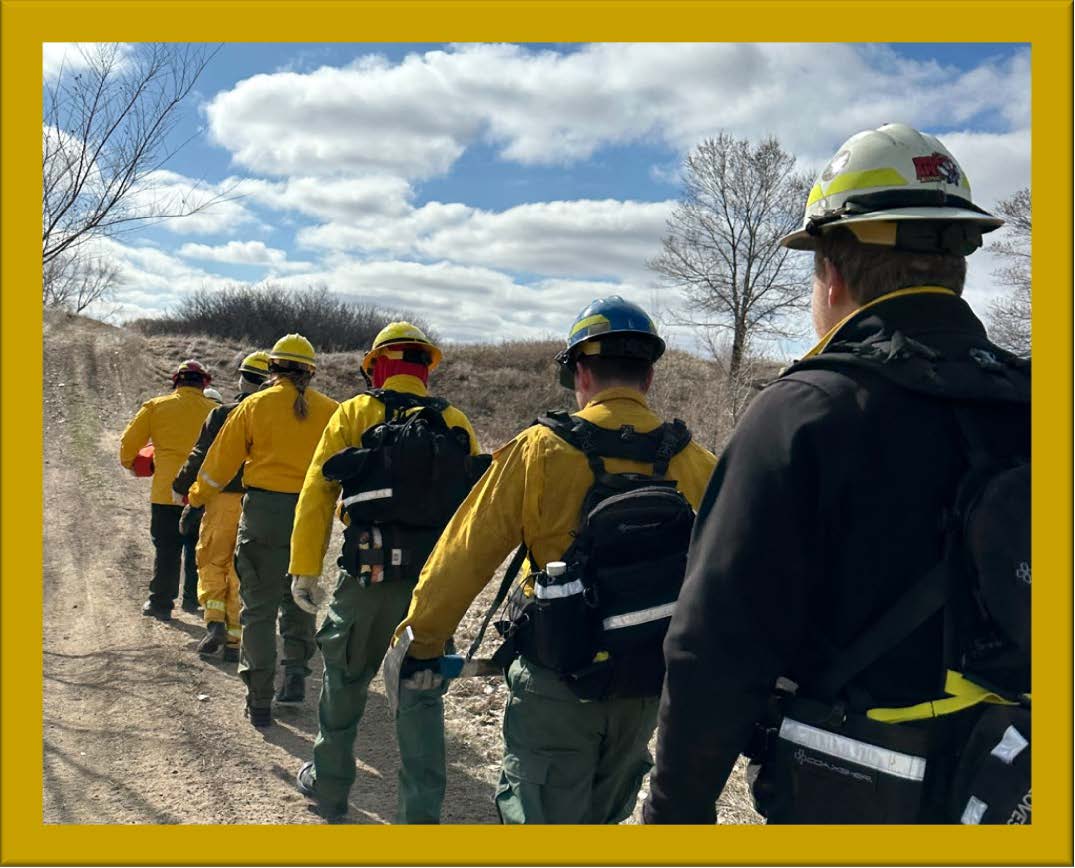 Image of wildland fire fighters marching along a dirt road