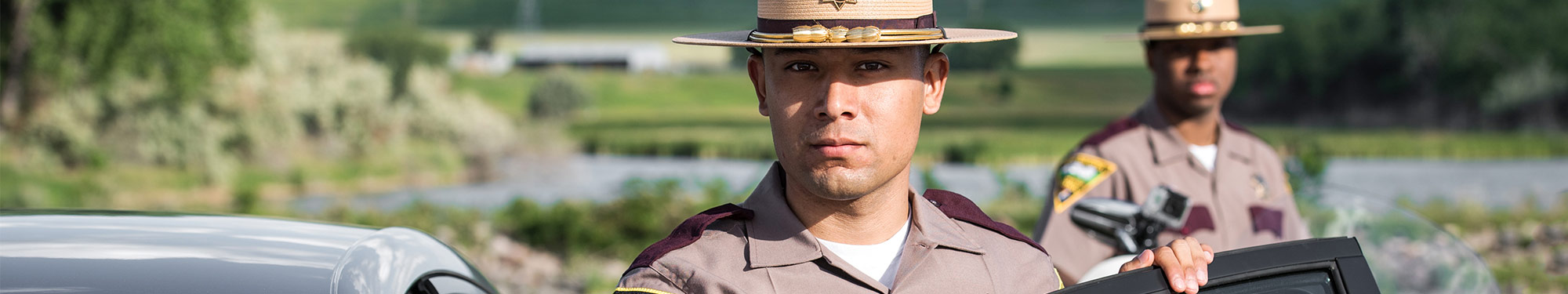 Image of Highway Patrol trooper standing by his patrol vehicle with the door open