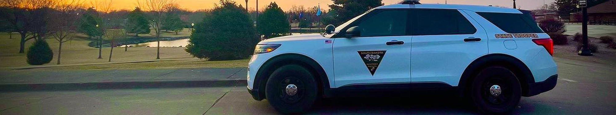 Image of white South Dakota Highway Patrol vehicle parked by Capitol Lake in Pierre