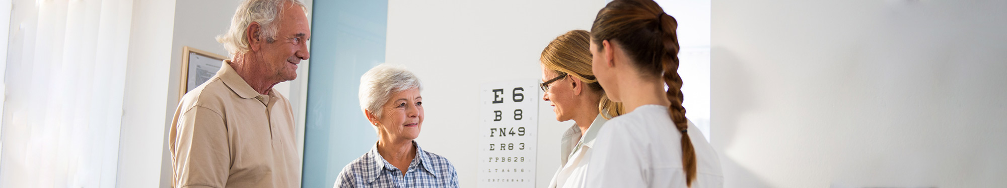 Image of elderly couple visiting with a doctor and a nurse in a clinical setting