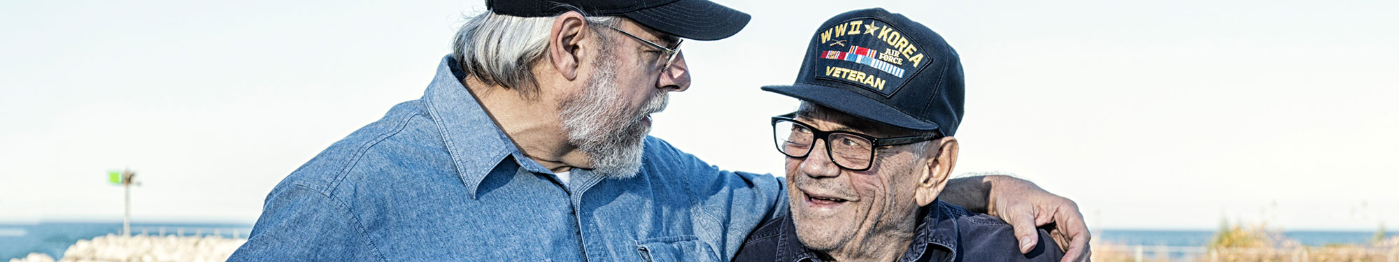 Image of one younger veteran with his arm around a World War 2/Korean War veteran in comradarie