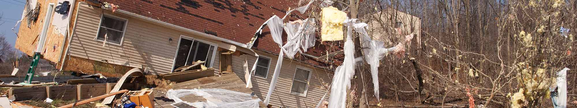 Image of a home after a tornado with debris in the yard and in the trees