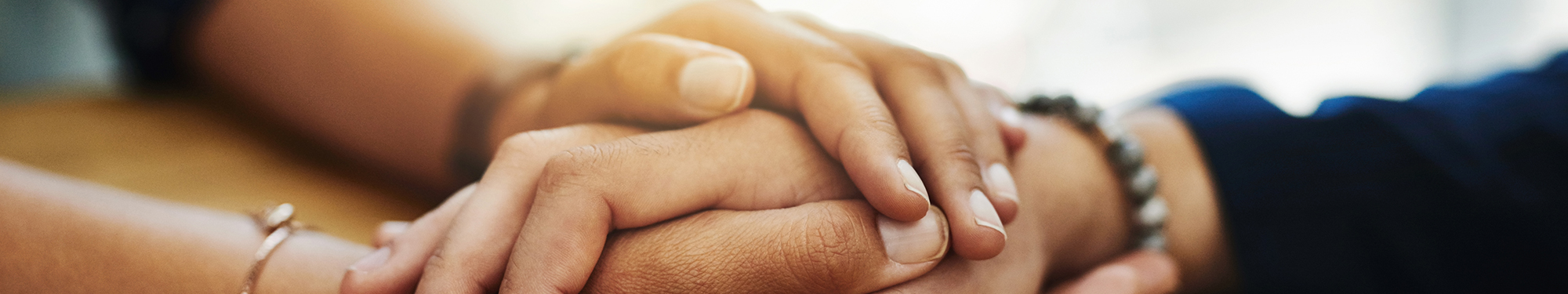 Image of one woman's hands folded over another woman's hands offering comfort and support