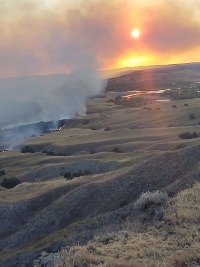 Aerial image of grassland fire burning with clouds of smoke obscuring the sun
